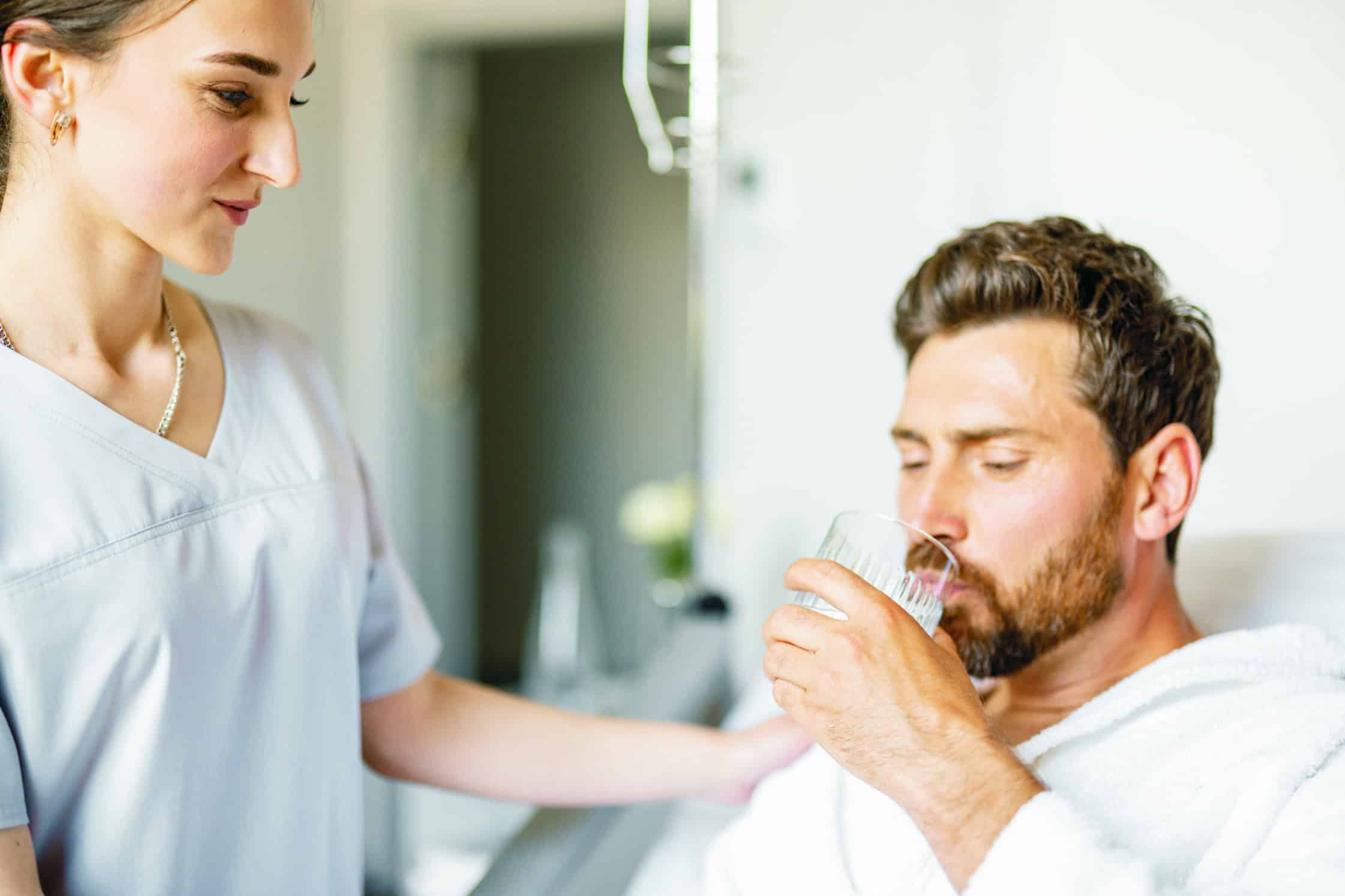 Woman assisting a man taking glass of water